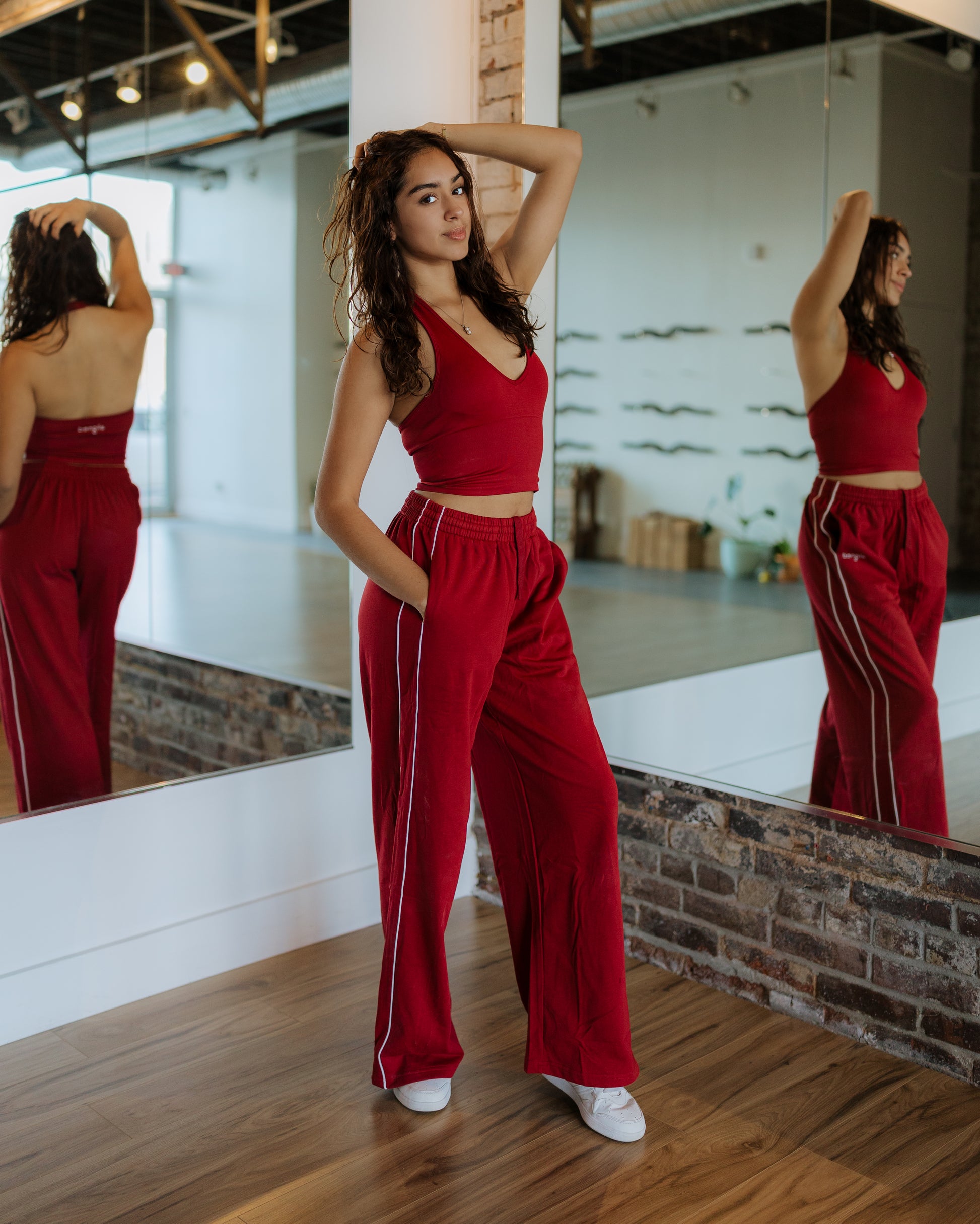 Woman wearing red athleisure set standing in front of mirror