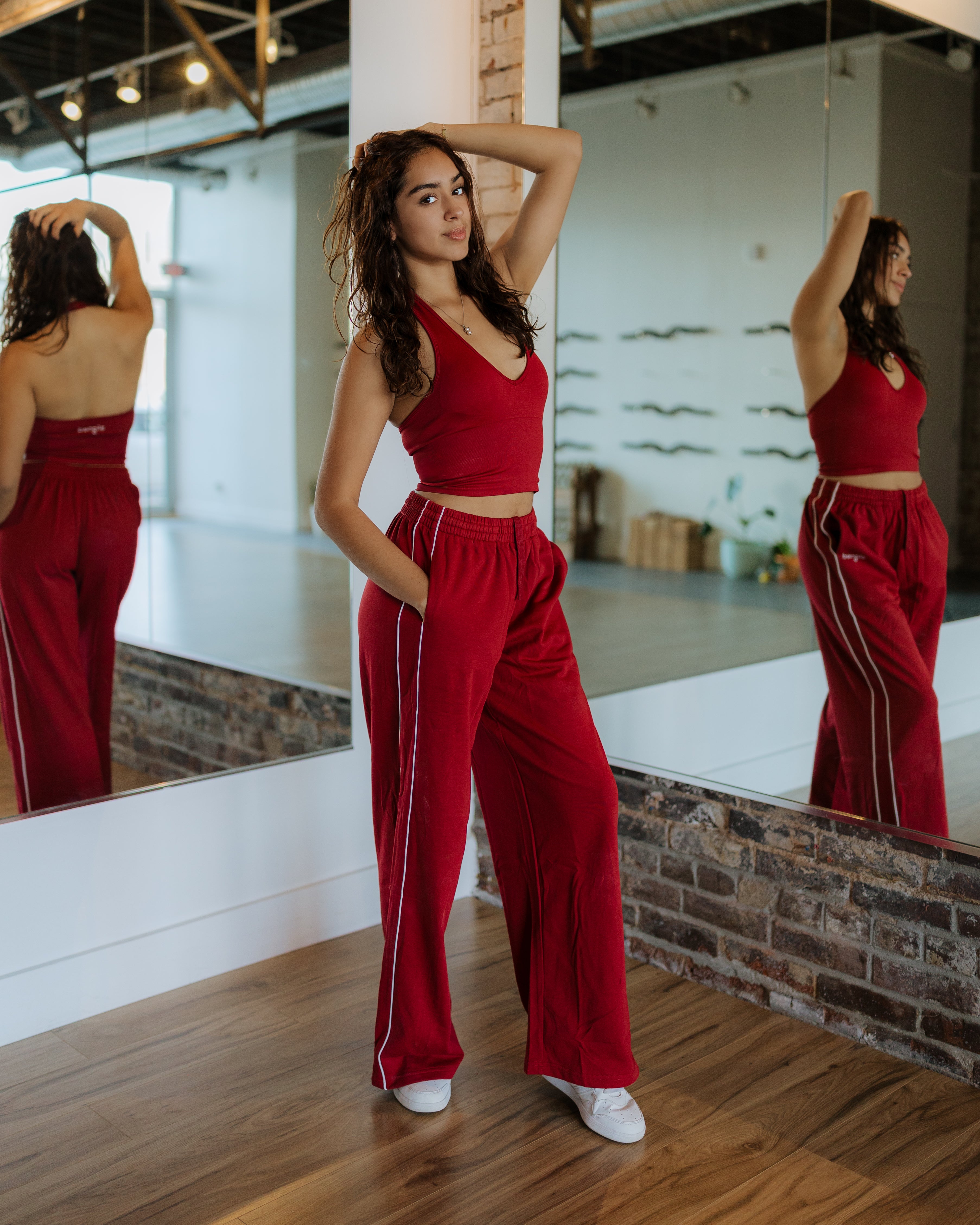 Woman wearing red athleisure set standing in front of mirror