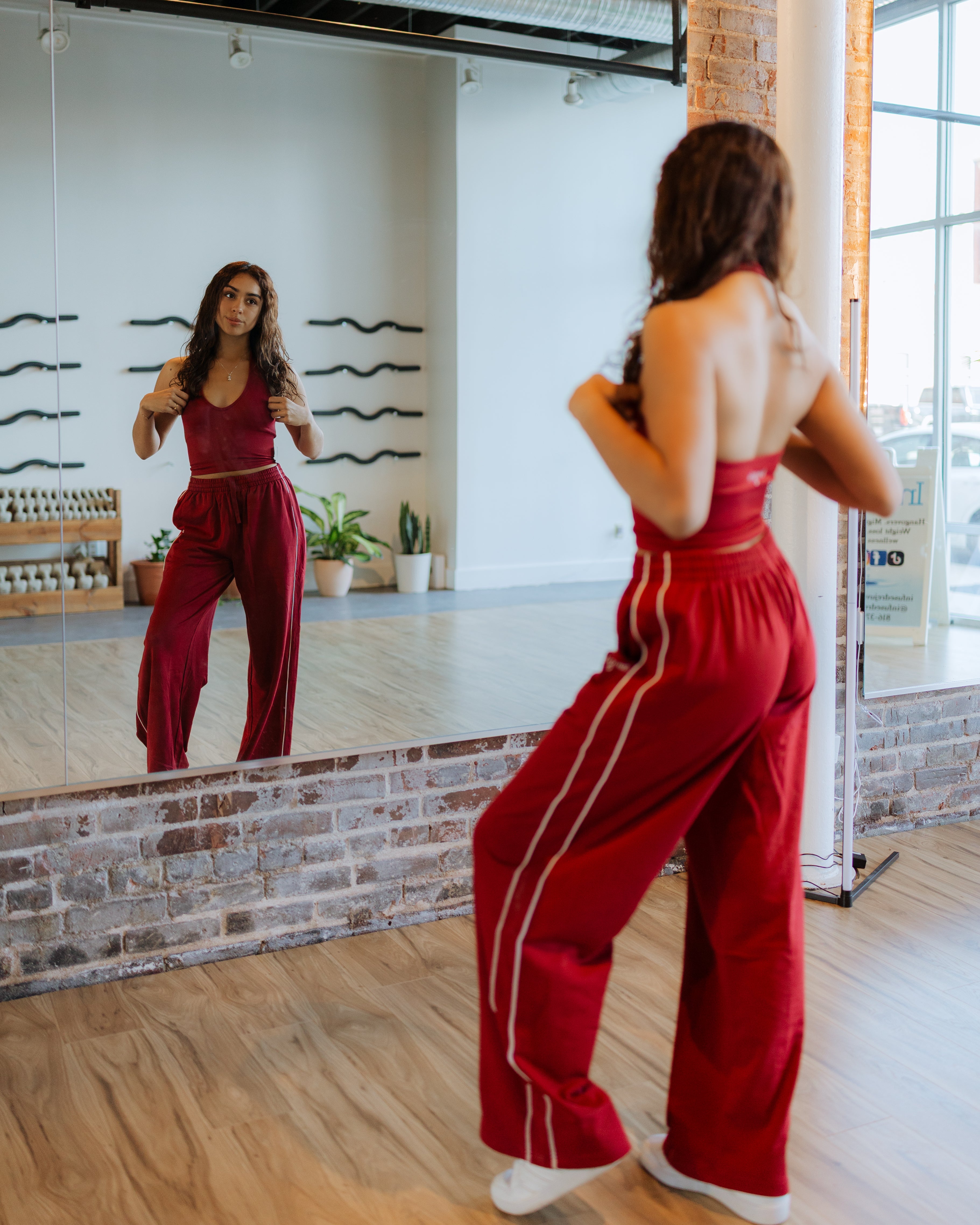 Woman wearing red athleisure set standing in front of mirror
